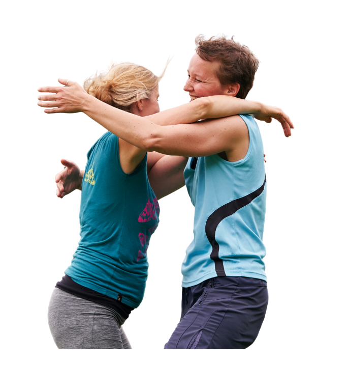 Two women in sports clothing hug in celebration.
