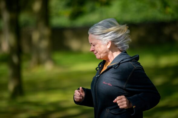 A woman runs through a green landscape.