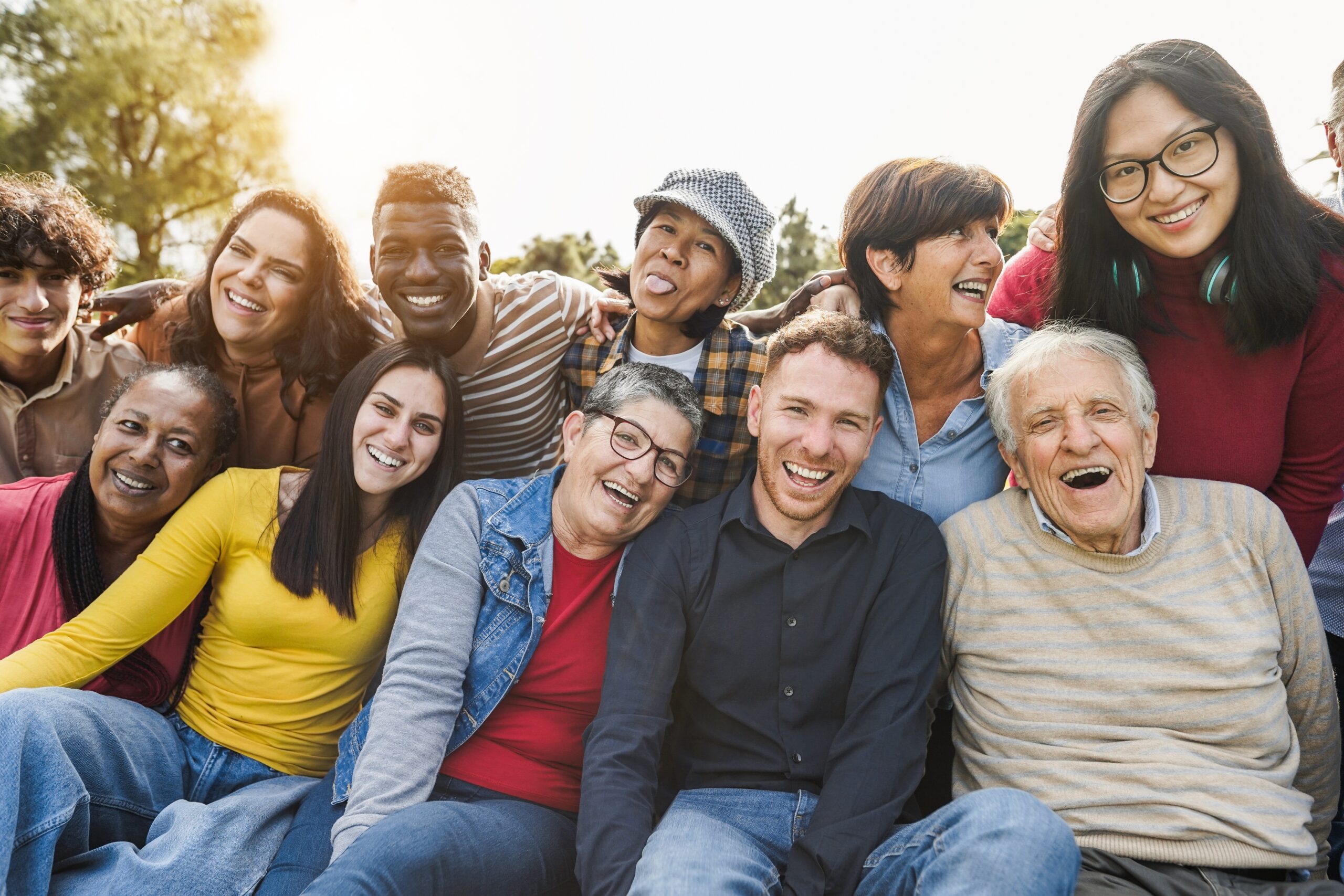 A group of people enjoy the sunshine outdoors and pose for the camera. They are smiling and happy.